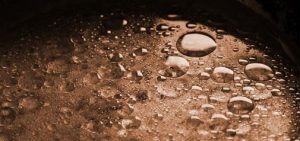 Oil droplets floating on surface water. (Photo by ehow.com)