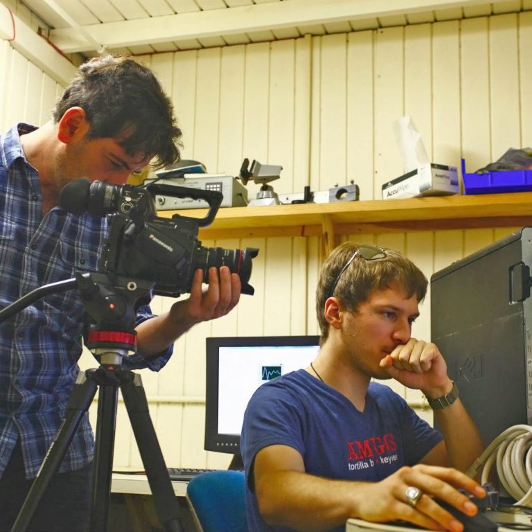 Ph.D. student Nathan Laxague is looking over salt-water tank images as producer Ali Habashi films footage for the CARTHE video. (Photo provided by CARTHE)