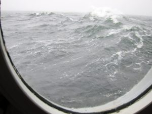 Breaking surface waves, generating whitecaps and ocean turbulence as seen from a ship's bull's eye. (Photo by: Kai Christensen)