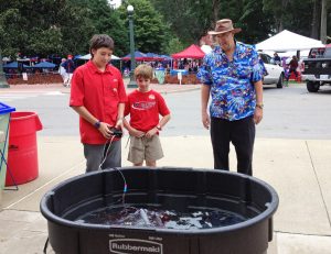 Science enthusiasts Yaniv Goulet (left) and Gilad Goulet (middle) operate an ROV they made at the University of Mississippi’s game against Alabama while their father, Dr. Denis Goulet, looks on. (Photo credit: Michelle Edwards)