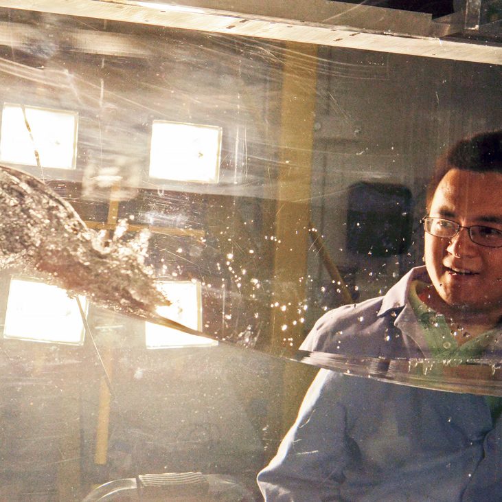 In an acrylic wave tank he designed and built himself at the Johns Hopkins Laboratory for Experimental Fluid Mechanics, Cheng observes a mechanically generated breaking wave and its associated turbulent flows. (Photo credit: Trevor Holmgren)