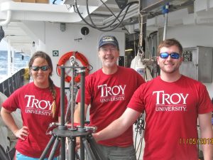 Professor Stephen Landers (center) and graduate students Ceil Martinec (left) and Craig Schimmer (right) onboard the NOAA ship Pisces in 2013. They used the displayed multicorer to collect sediment samples in the Gulf of Mexico. (Photo provided by Stephen Landers)