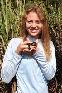 Lexi poses with a baby alligator during an alligator release trip. Other graduate students Lexi works with treat alligator eggs with mixtures of oil, Corexit, and other environmental contaminants to assess their effects on development. Lexi enjoys taking a break from the lab to help on release and egg collection trips. (Provided by: Lexi Temkin)
