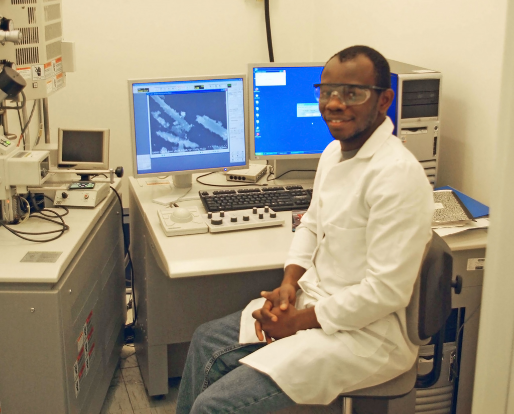 Sehinde, at the Tulane University Coordinated Instrumentation Facility, sits beside the scanning electron microscope he uses to image halloysite nanotubes and oil droplets stabilized by them. (Photo by Chike Ezeh)