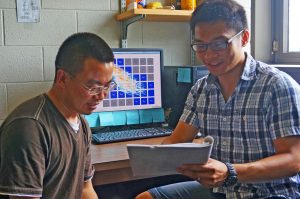 Bicheng (right) discusses his research with a colleague. A new technique that he is using to track oil plumes is visible on the monitor behind them. (Provided by Bicheng Chen)