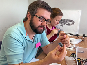 Christopher Hatten of Mildred Osborne Charter School contemplates the Arduino microcontroller board that he will later program to run his SeaGlide model. (Photo by Dinah Maygarden)