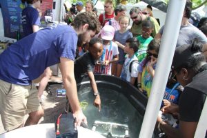 ECOGIG marine scientists from Temple University talk about the tools they use to collect information about deep water ecosystems. Here, a student drives a model ROV (remotely operated vehicle) at the 2017 Philadelphia Science Carnival. Photo by ECOGIG.