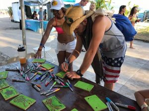 Visitors at Rock the Ocean’s Tortuga Music Festival learned about CARTHE drift cards. Here, folks color their own design on drift cards used for the Bay Drift project. Photo by CARTHE.