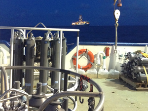 CTD-Rosette_rig_slider Researchers used CTD and Niskin bottle rosettes to collect dissolved organic carbon samples aboard the R/V Pelican. In the distance is a nearby drilling ship on the Gulf of Mexico. Photo credit: Brad Rosenheim