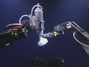 This image shows the gas bubble collection apparatus on the left and the remotely operated vehicle (ROV) sampling arm on the right. Cameras mounted on the ROV Hercules took this underwater photo. Credit: Ocean Exploration Trust, Inc.