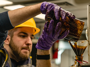 Master’s student Matthew Kurpiel, Coastal Carolina University, pours oil and seawater into a funnel that separates the fluids. (Used with permission from photographer Jason Gonzales iamjgvisuals.com.)