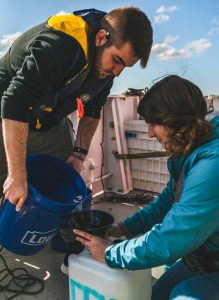 Coastal Carolina master’s students Matthew Kurpiel (left) and Elana Ames (right) collect bucket cast samples of an oil sheen above the GC600 seep field. (Provided by Matthew Kurpiel)